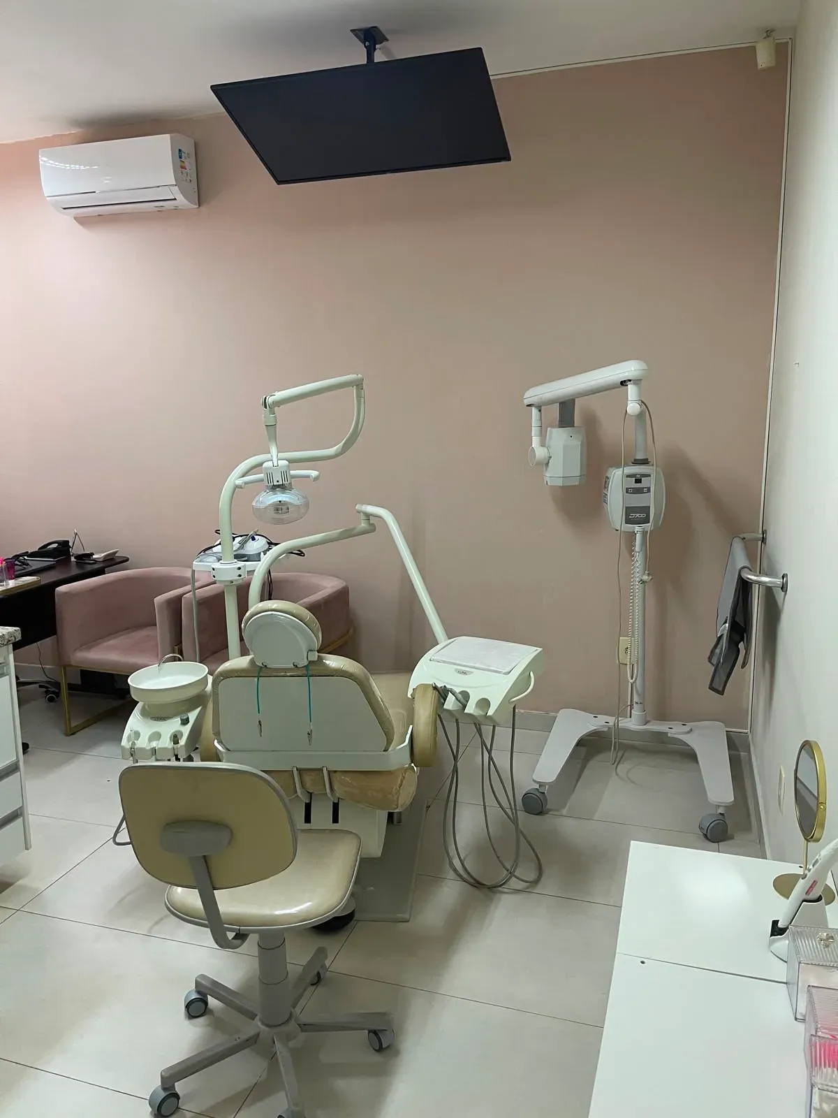 Consultório onde a Dra. Amanda Tainara atende, com cadeira odontológica, aparelho de raio-X, ar-condicionado e televisão fixada no teto
